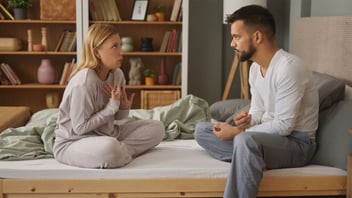 Couple sitting cross legged on a bed having a calm, serious conversation about their relationship
