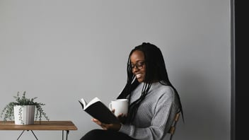 Woman smiling while enjoying a quiet moment reading with a cup of coffee
