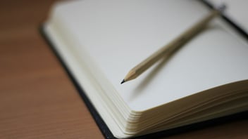 Open notebook with blank pages and a pencil resting on top