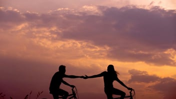 Couple on bikes reaching for each other's hands