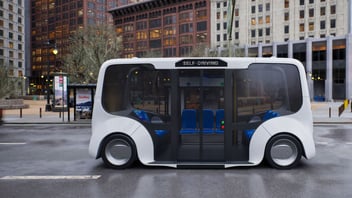Small self driving shuttle bus traveling down a city street