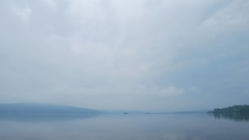 Still water surrounded by trees and sky