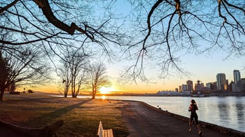 Person jogging along a waterfront path at sunrise