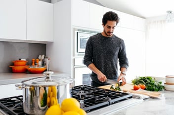 Man chopping fresh vegetables at a bright kitchen counter