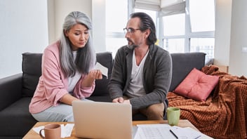 Couple reviewing their finances together at a laptop in the living room