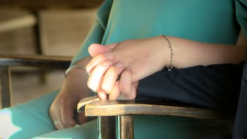 Couple holding hands closely in warm light, a quiet moment of support