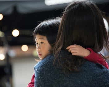 A mother hugs her young child close as the child rests against her shoulder