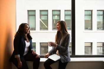 Two people sitting by a window, talking and laughing together