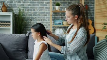Mother gently combing her daughter's hair