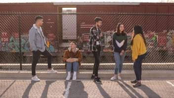 Teen friends together by a chain link fence