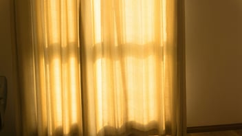 Warm morning sunlight glowing through bedroom curtains