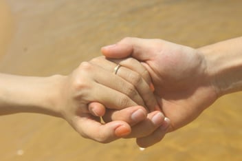 Two hands gently clasped together in warm sunlight