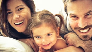 Smiling parents cuddling with their young daughter