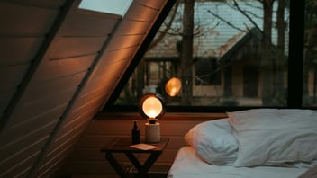 Cozy dim bedroom at night with a warm lamp glowing beside the bed