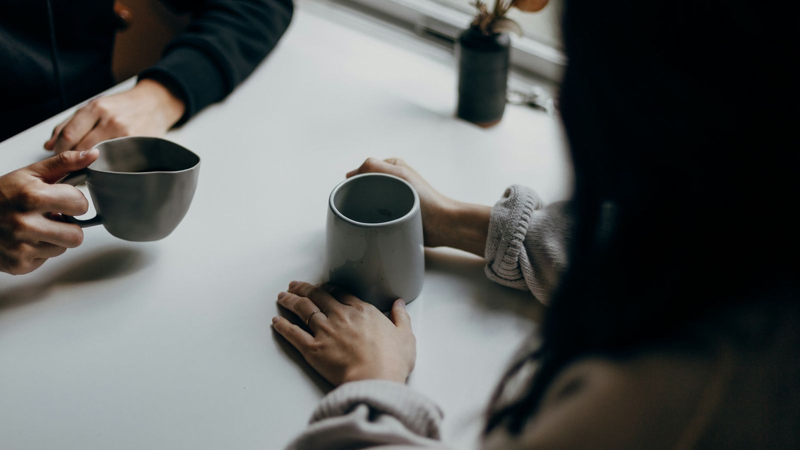 Two people talking over warm mugs at a table
