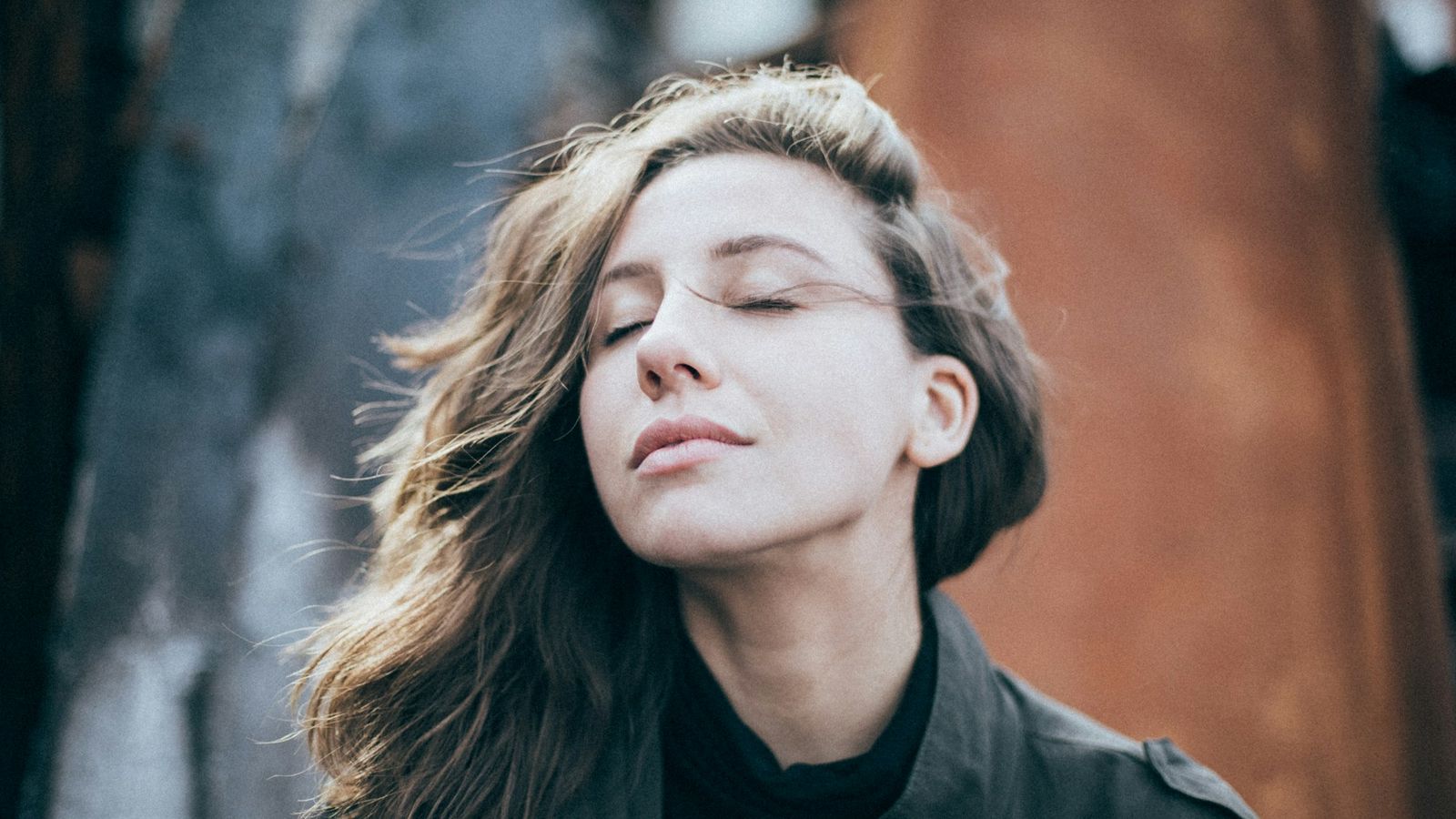 Woman with eyes closed taking a slow calming breath outdoors