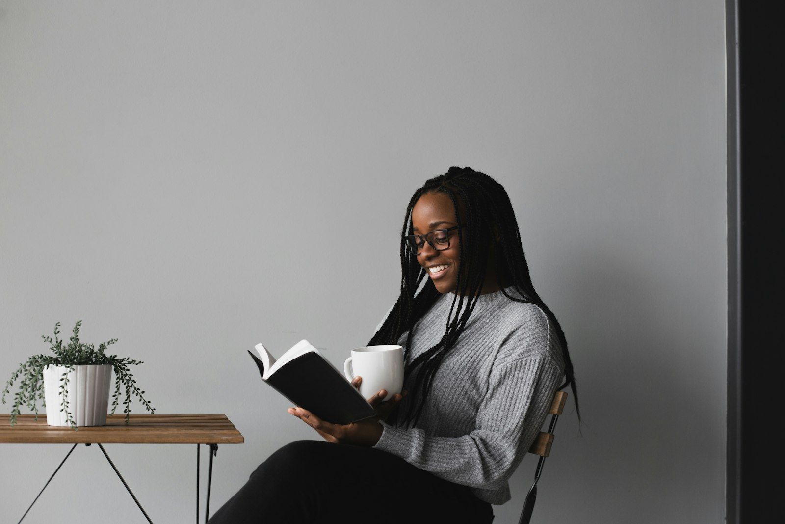 Woman smiling while enjoying a quiet moment reading with a cup of coffee
