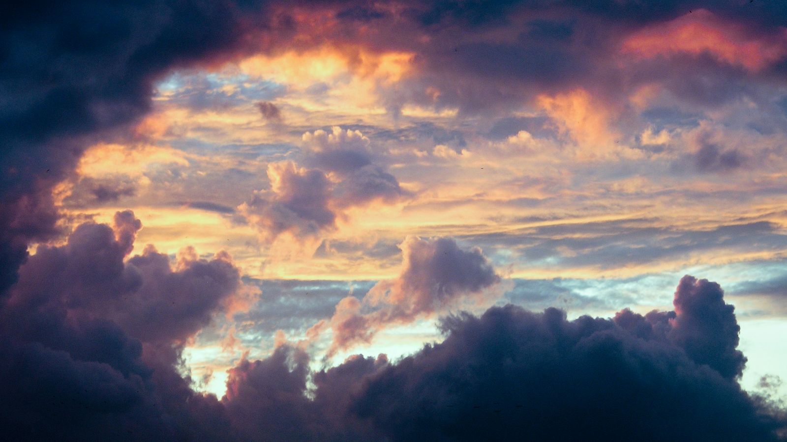dark storm clouds framing a patch of warm golden light in the sky