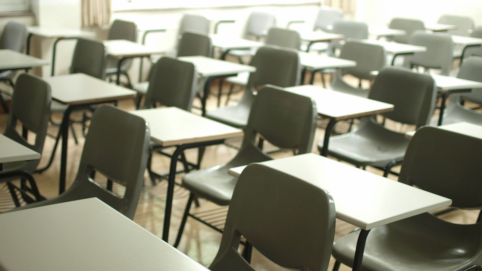 Bright, tidy classroom with white tables and black chairs