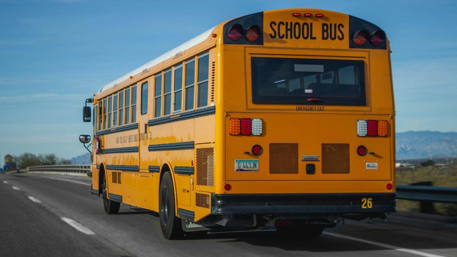 A yellow school bus travels down the road on a clear morning