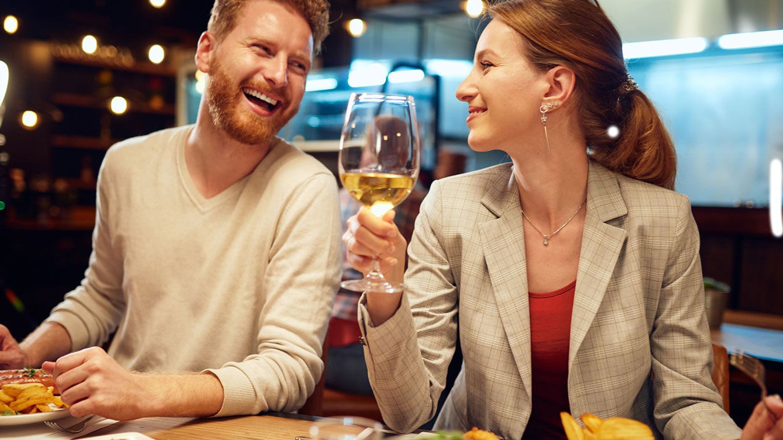Smiling man and woman sharing a laugh over dinner and wine at a restaurant