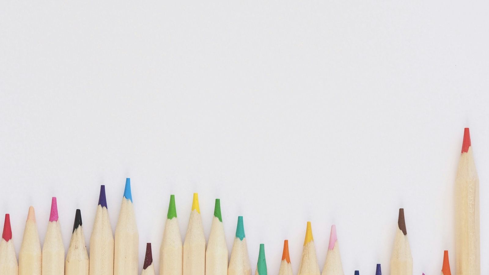 Colored pencils lined up neatly on a white desk