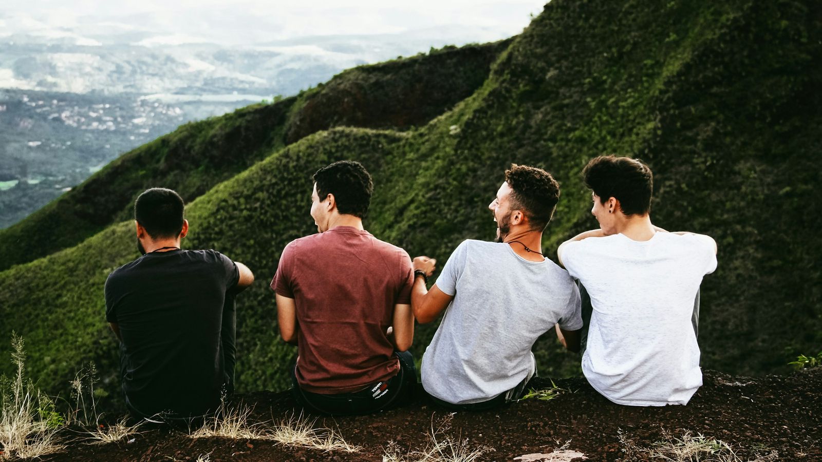 Four men laughing together on a mountain trail