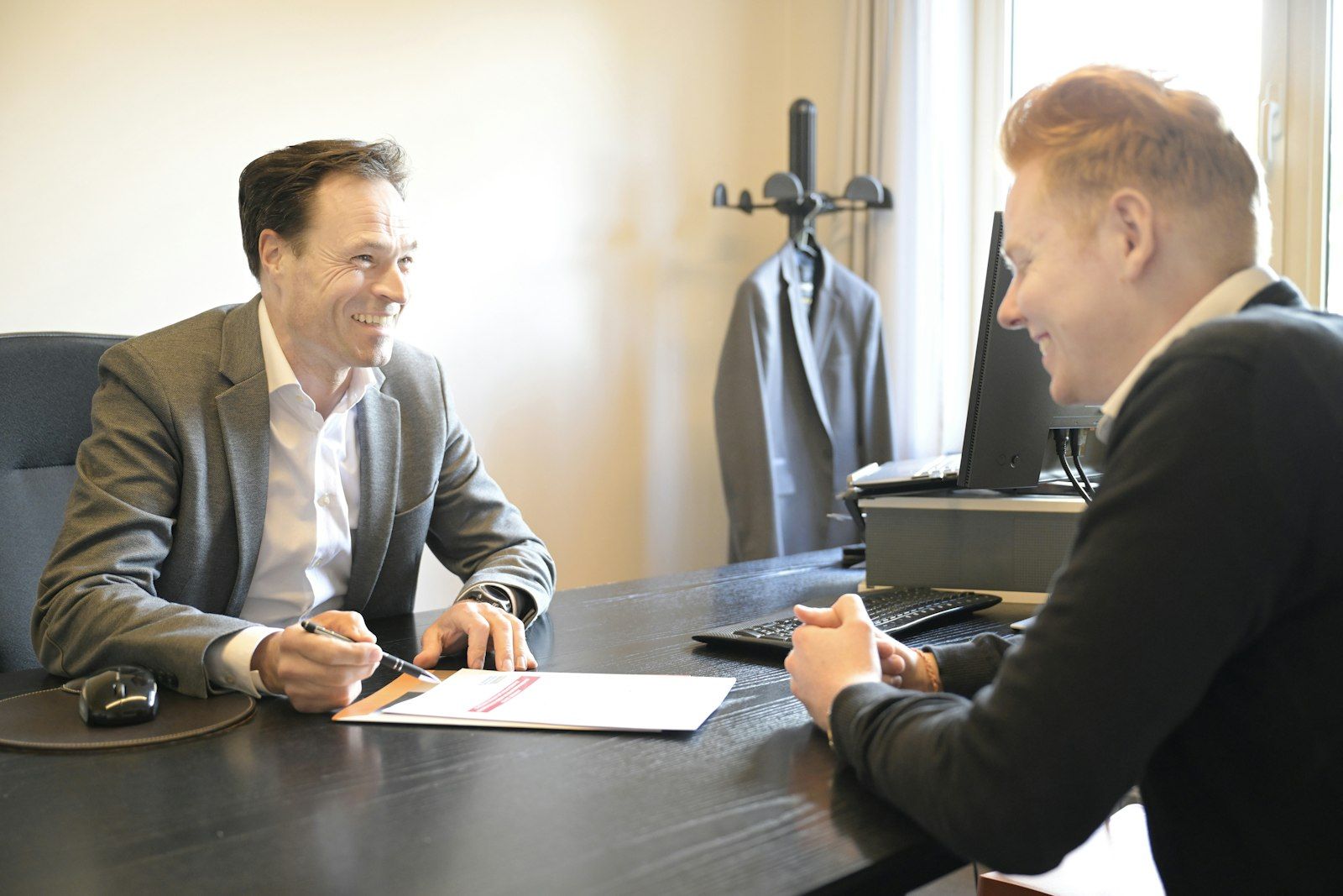 Counselor and adult client reviewing pages of notes together at a desk in a bright office