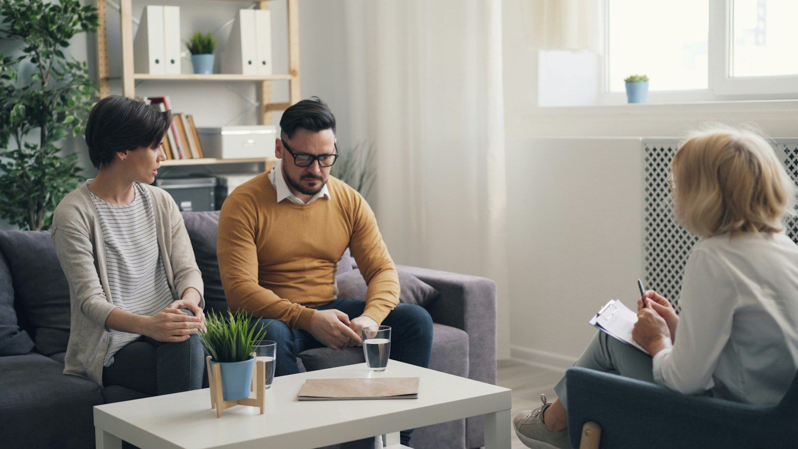 Married couple sitting together and talking with a counselor in a calm office