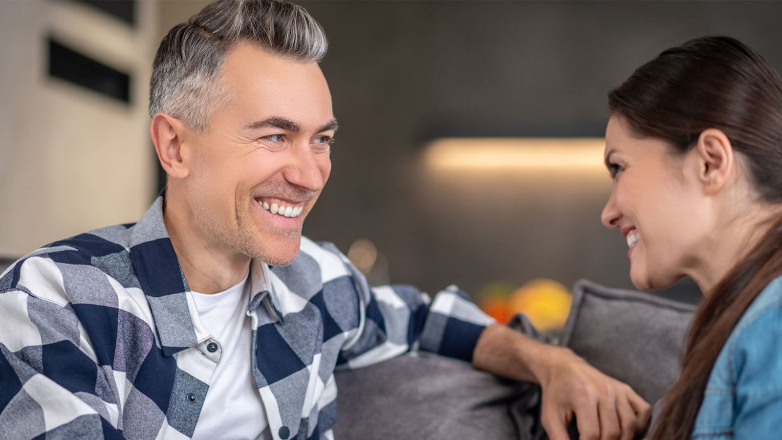 A man and a woman talk warmly together on a couch during a supportive conversation