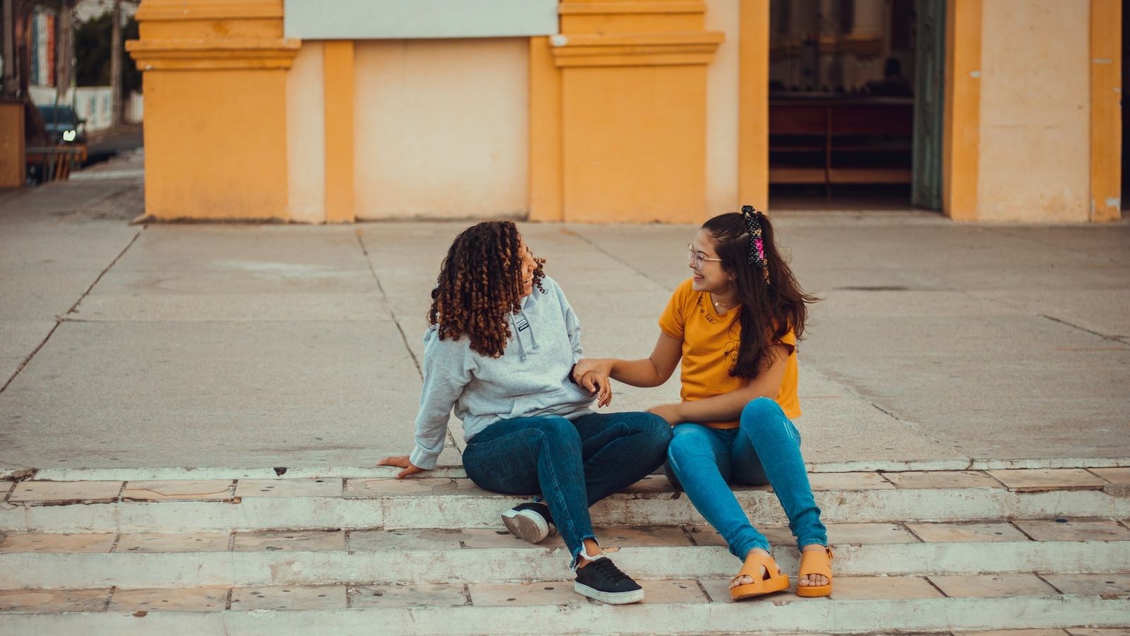 Two teenagers sitting on steps outside having a supportive conversation
