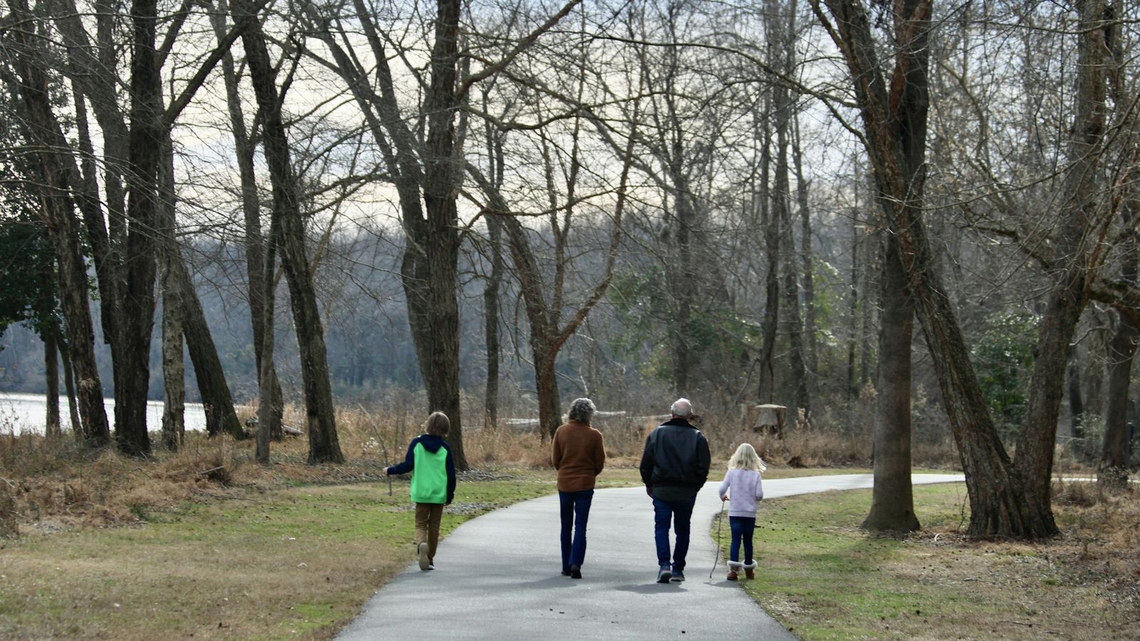 Family of four walking together along a wooded park path