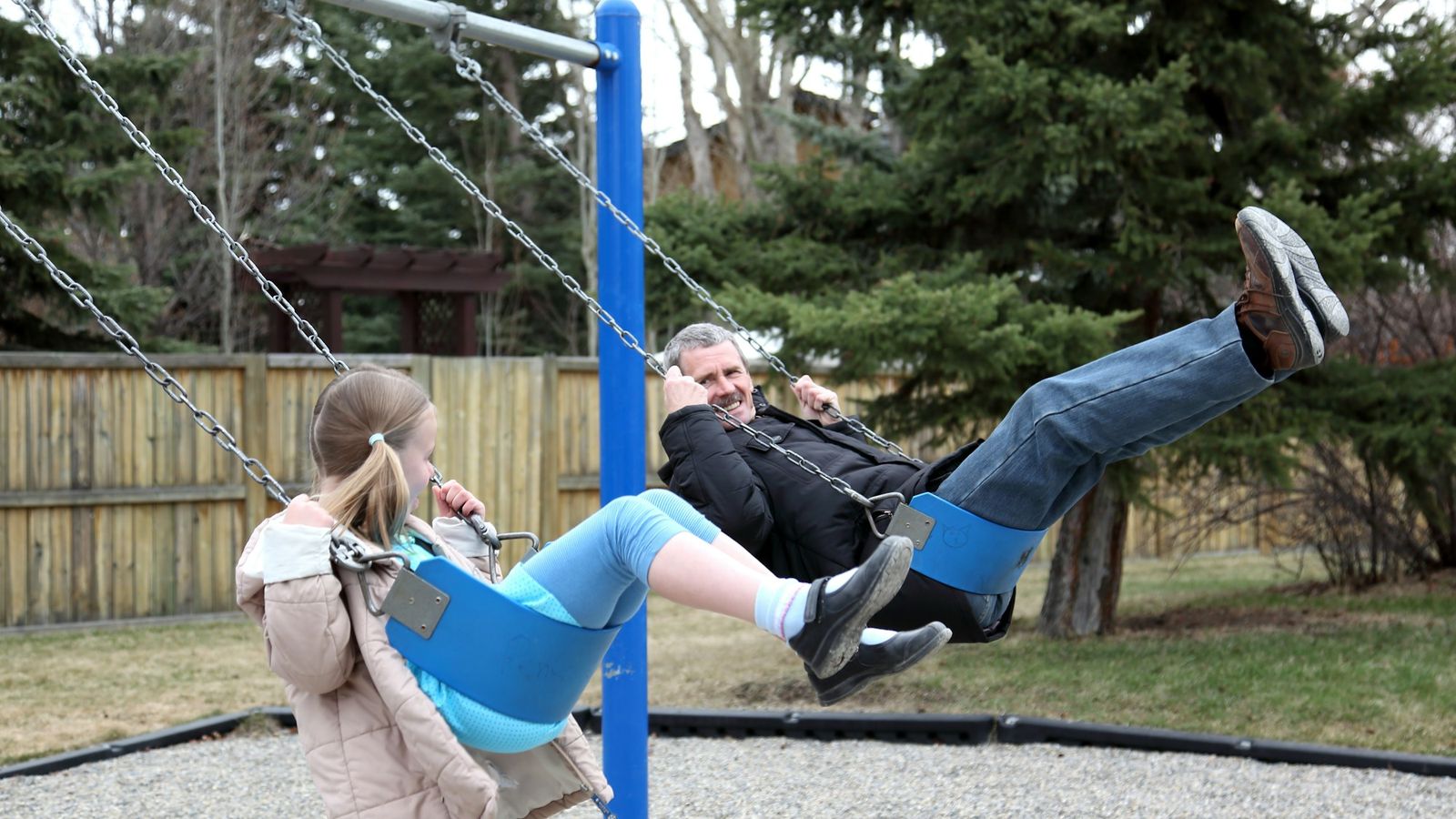 Father and daughter on playground swings