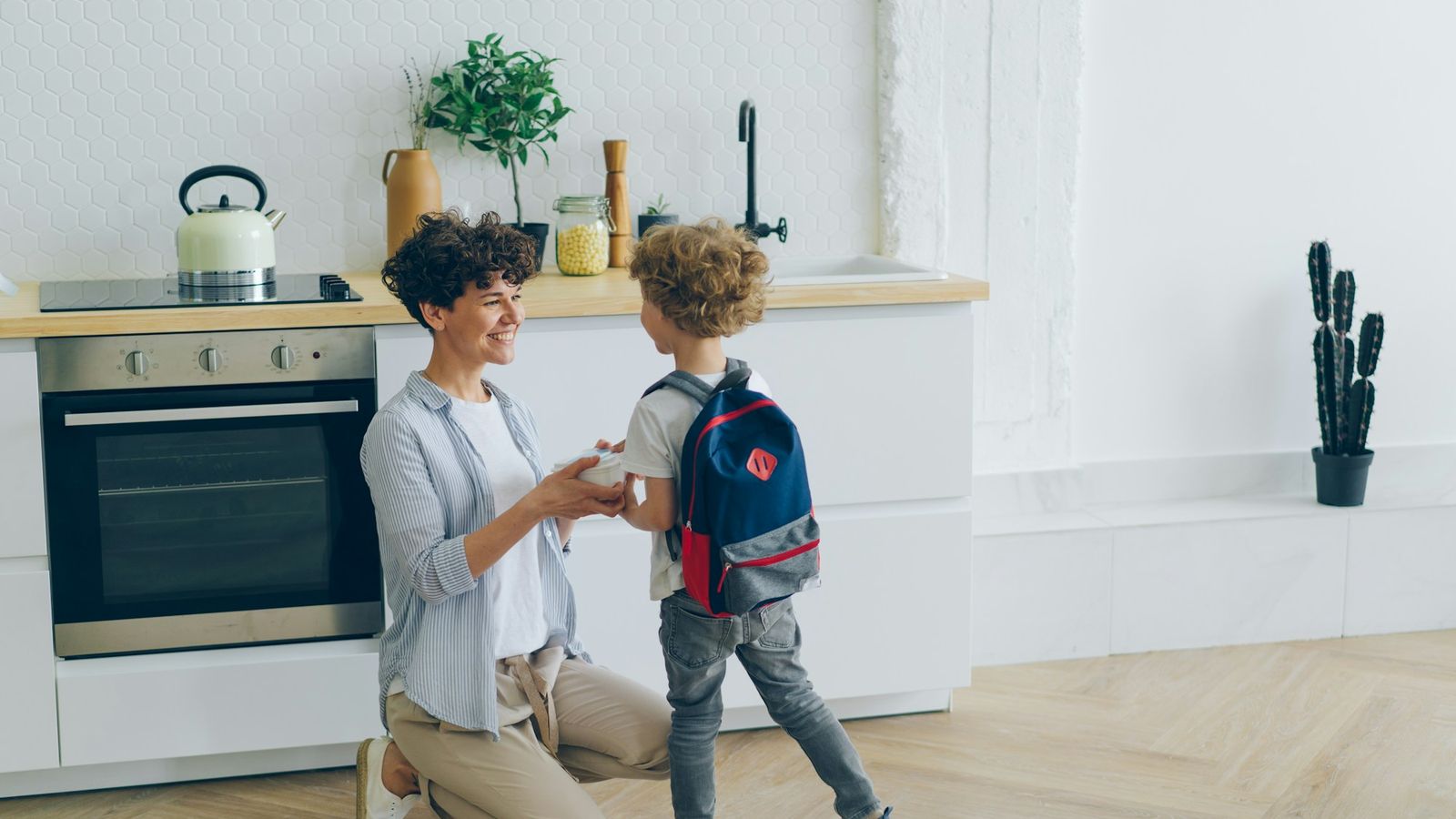 a mother handing her son a lunch box before school