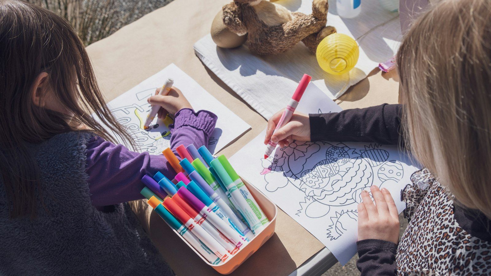 Two children coloring together with bright markers at a table