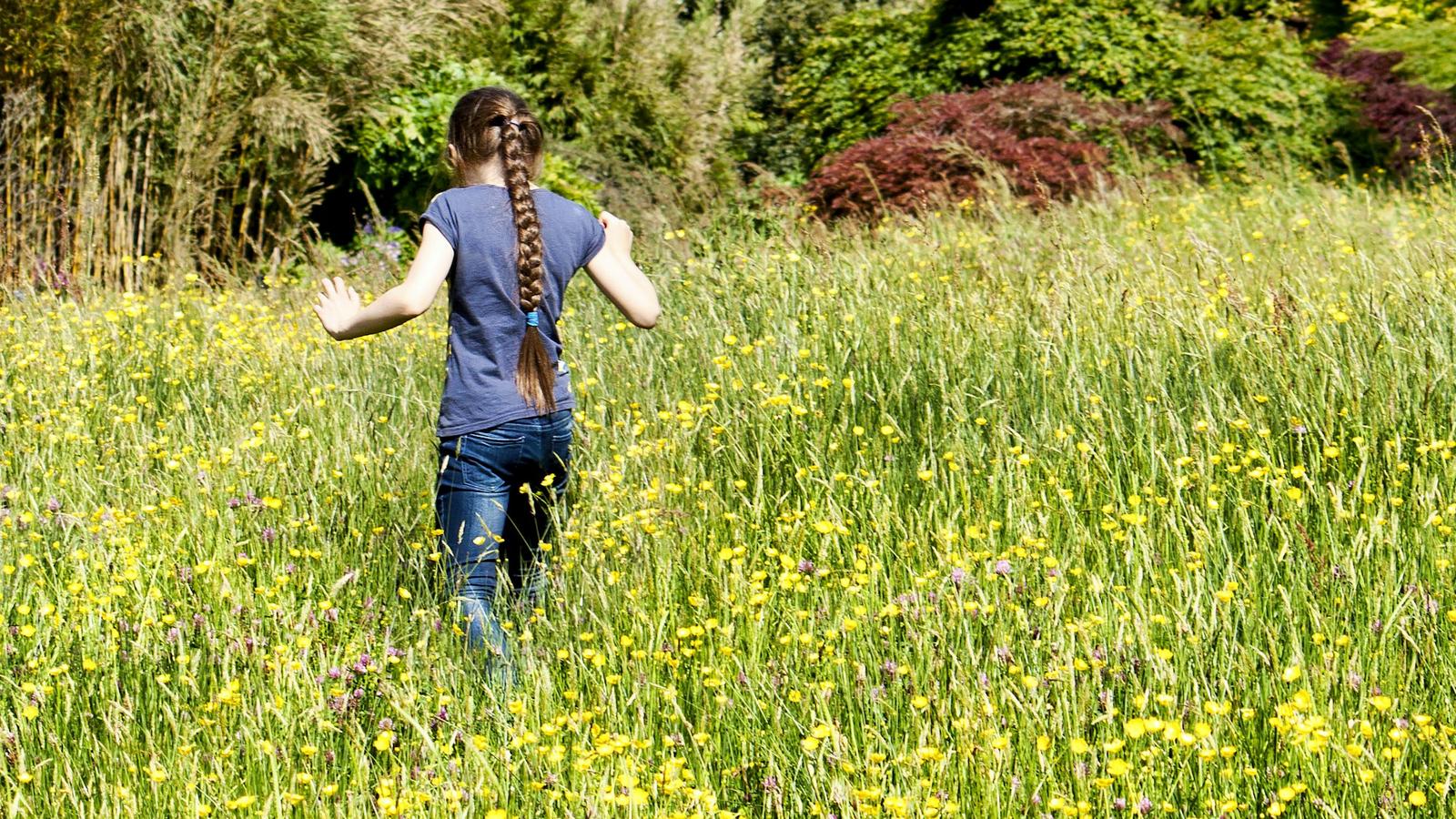 Girl running happily through a summer wildflower field