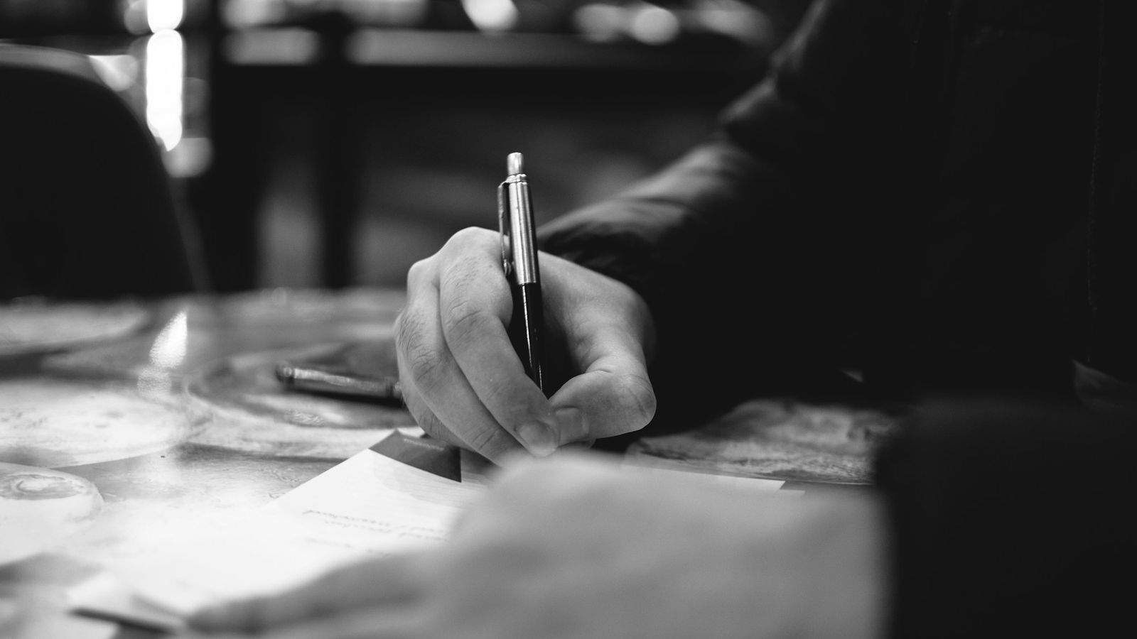 Close-up of hands reviewing and signing paperwork at a desk