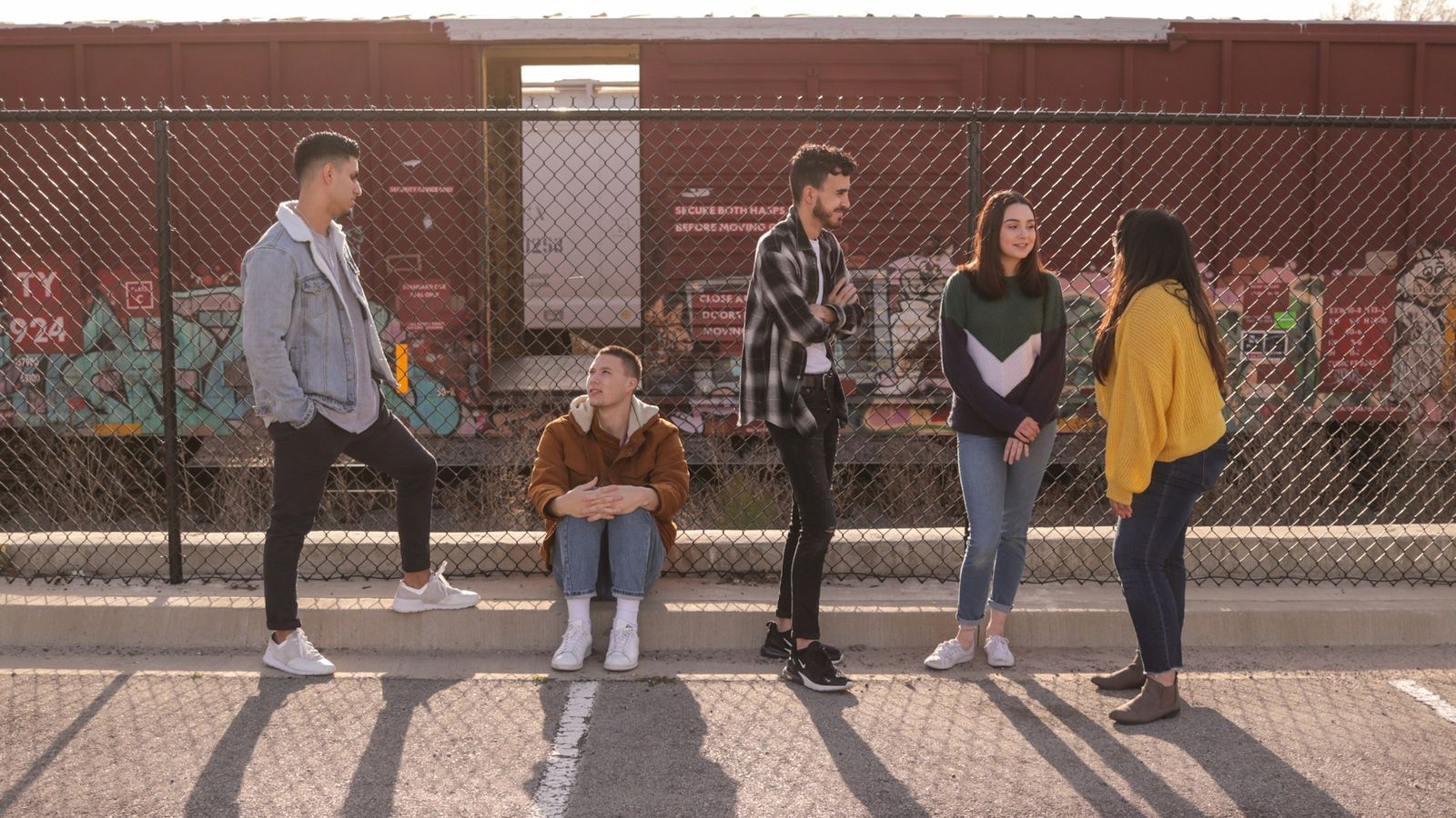 Teen friends together by a chain link fence