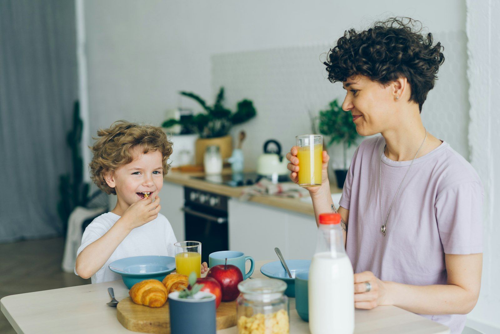 Mother managing the morning breakfast routine with her young son in the kitchen