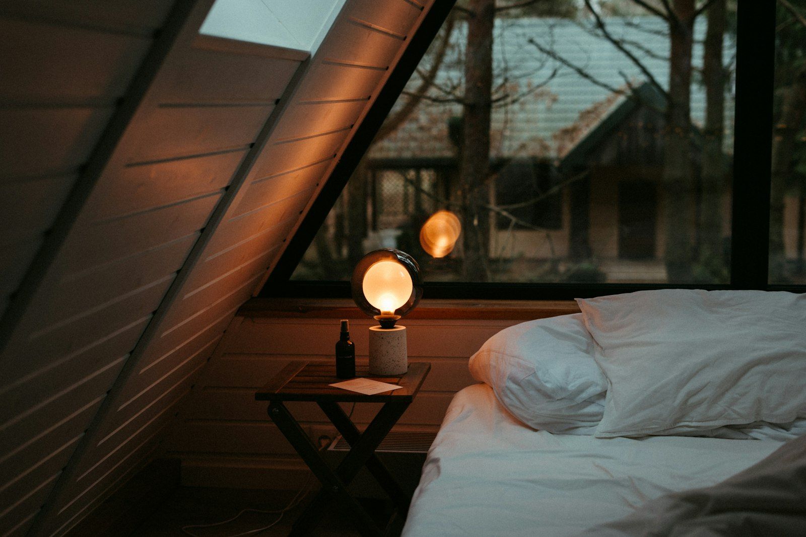 Cozy dim bedroom at night with a warm lamp glowing beside the bed