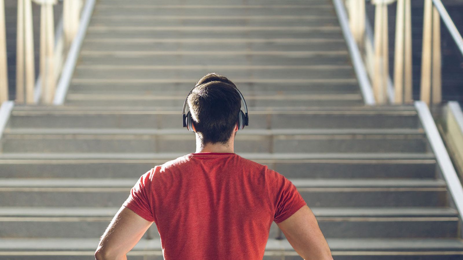 Person wearing headphones at the base of a long outdoor staircase, ready to climb